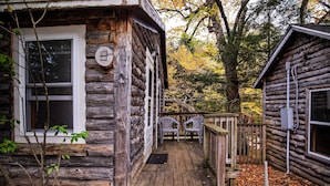 A rustic cabin with a wooden deck, two chairs, and a small porch area. - Pemi Cabins (Lincoln)