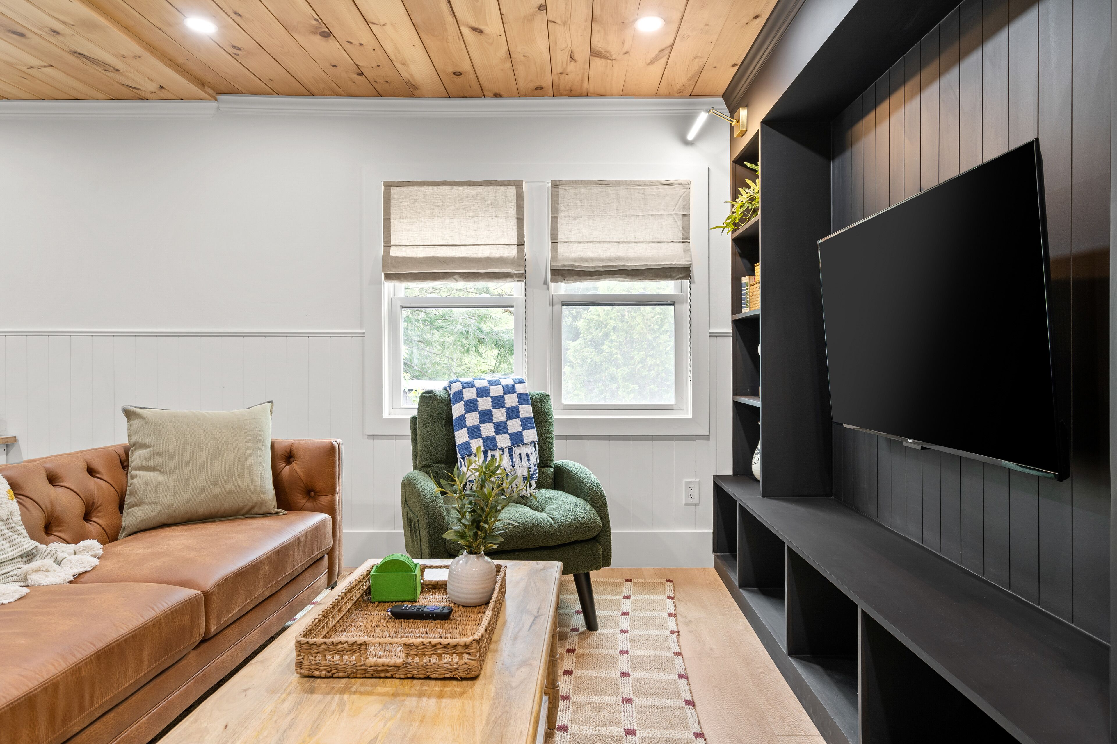 A living room with a brown leather sofa, a green armchair, a wooden coffee table, a flat-screen TV, and a fireplace.