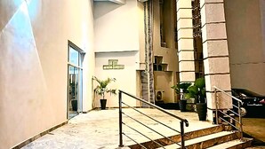 Eine großzügige Lobby mit einer Marmortreppe, einer hohen Decke mit eingelassener Beleuchtung und einer großen Pflanze in einem Topf.