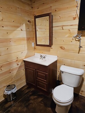 A wooden-paneled bathroom with a white sink, dark wooden cabinet, and a white toilet.