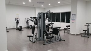 A gym with various exercise machines, a bench, and dumbbells. - Three-Bedroom Apartment - The Aliff Residences

 (Johor Bahru)