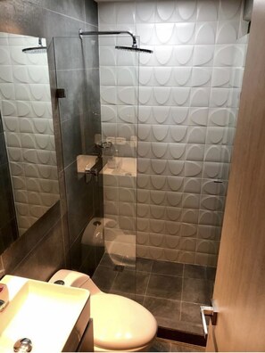 Enjoy a refreshing shower in the sleek bathroom with a glass-enclosed shower, toilet, and sink.