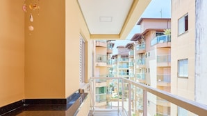 A balcony with a marble countertop and wooden stools, overlooking a residential area with multiple balconies. - Madagascar (Ubatuba)