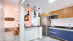 A modern kitchen with a stainless steel refrigerator, wooden cabinets, and pendant lighting. - Madagascar (Ubatuba)