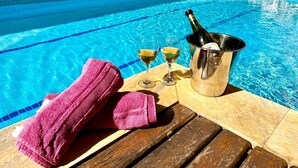 A poolside setting with a wooden deck, a metal bucket with a bottle, and two glasses of a clear liquid, likely wine, on a wooden table. - Madagascar (Ubatuba)