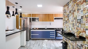 A modern kitchen with blue cabinets, a black countertop, and pendant lighting. - Madagascar (Ubatuba)