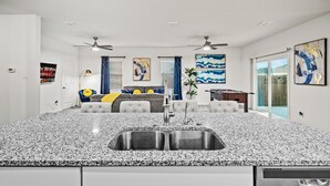 Eine moderne Küche mit Granit-Arbeitsplatten, einer Spüle mit zwei Becken und einem Essbereich mit Sofa und Couchtisch.