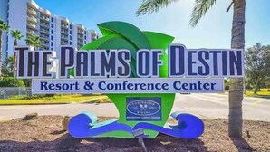 A sign for The Palms of Destin Resort & Conference Center with a logo and text.