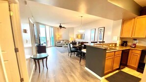 A spacious kitchen with wooden cabinets, a dining area with a round table, and a large window providing natural light.