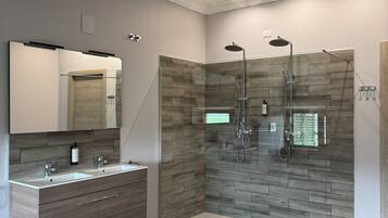 A modern bathroom with a glass-enclosed shower, a vanity with a mirror, and a wooden floor.