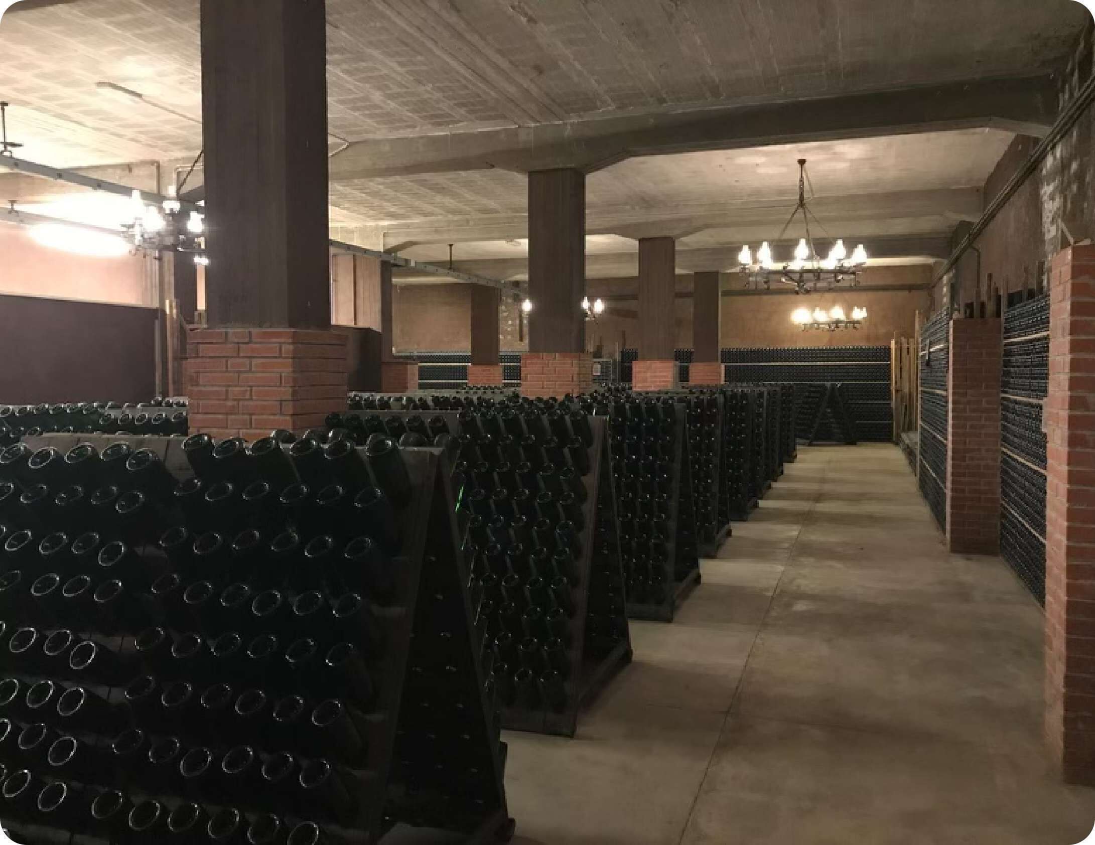 Une cave à vin avec des rangées d’étagères à bouteilles et un mur en briques.