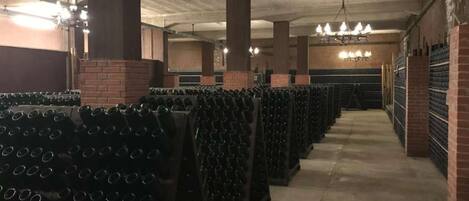 Una cava de vinos con estanterías llenas de botellas y una pared de ladrillo.