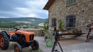 Un edificio de piedra con una terraza, un tractor y una cámara sobre un trípode.