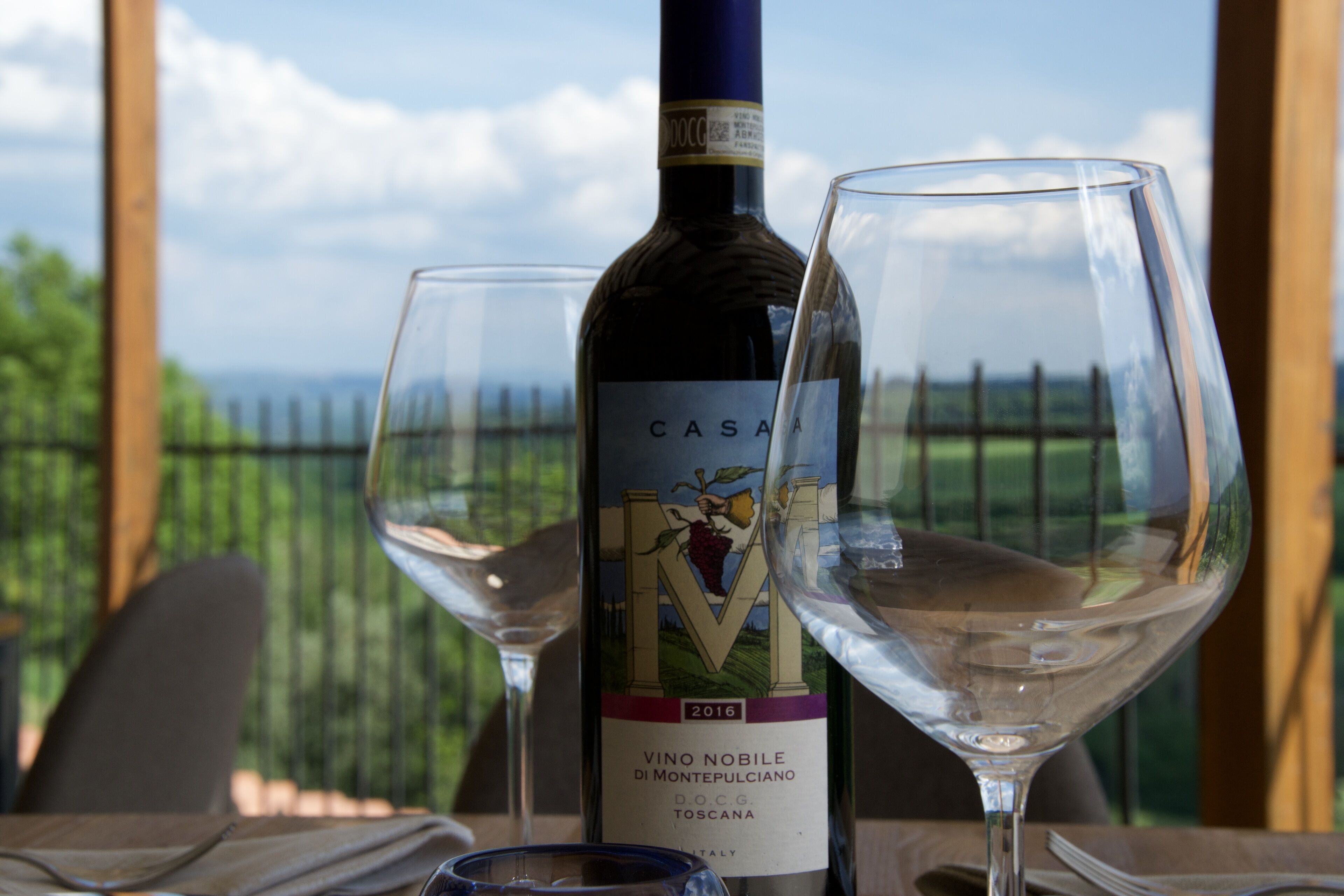 Una bottiglia di vino e due bicchieri su un tavolo con vista panoramica sullo sfondo.