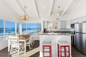 Una cocina espaciosa con una isla grande, armarios blancos y vistas al océano.