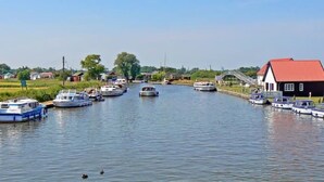 A canal with boats docked on both sides, a bridge, and a house with a red roof. - Exceptional Chalet 5 min walk to beach, short drive to the Broads & Gt Yarmouth (Yarmouth)
