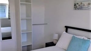A hotel room with a neatly made bed, a white wardrobe, and a small bedside table with a lamp. - Exceptional Chalet 5 min walk to beach, short drive to the Broads & Gt Yarmouth (Yarmouth)