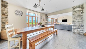 A spacious dining area with a wooden table, benches, and a stone wall.