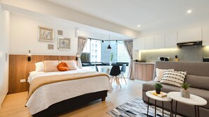 A modern hotel room with a bed, a sofa, a small dining table, and a kitchen area. - ALU Apartments - Miraflores Central (Lima)