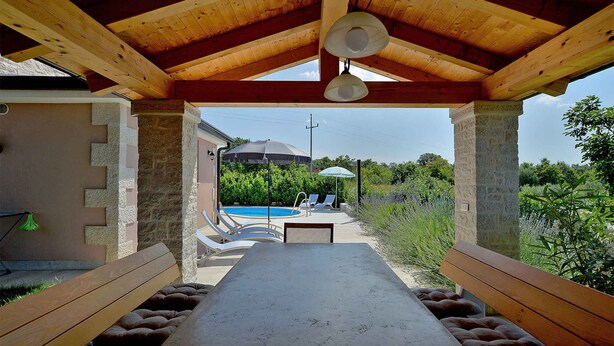 A covered outdoor dining area with a pool in the background. - Villa mit Pool und Klimaanlage (Kosinožići)