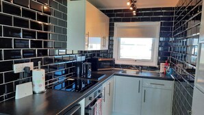 A modern kitchen with black tiled backsplash, white cabinets, and a window providing natural light.