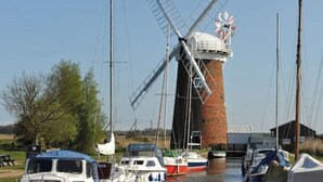 A windmill with boats docked nearby.