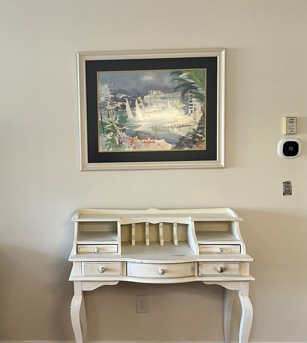 A framed painting of a coastal scene above a white dresser with multiple drawers and a built-in shelf. - Stunning 2/2 Carlton Lakes Condo: Your Naples, FL Paradise Awaits! (Naples)