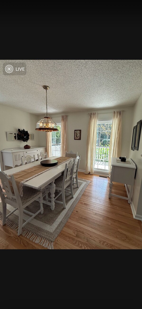 A dining area with a wooden table, chairs, and a hanging light fixture.