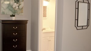 Un baño con un mueble de madera oscura, una obra de arte de mármol, un lavabo blanco y un espejo con marco negro.