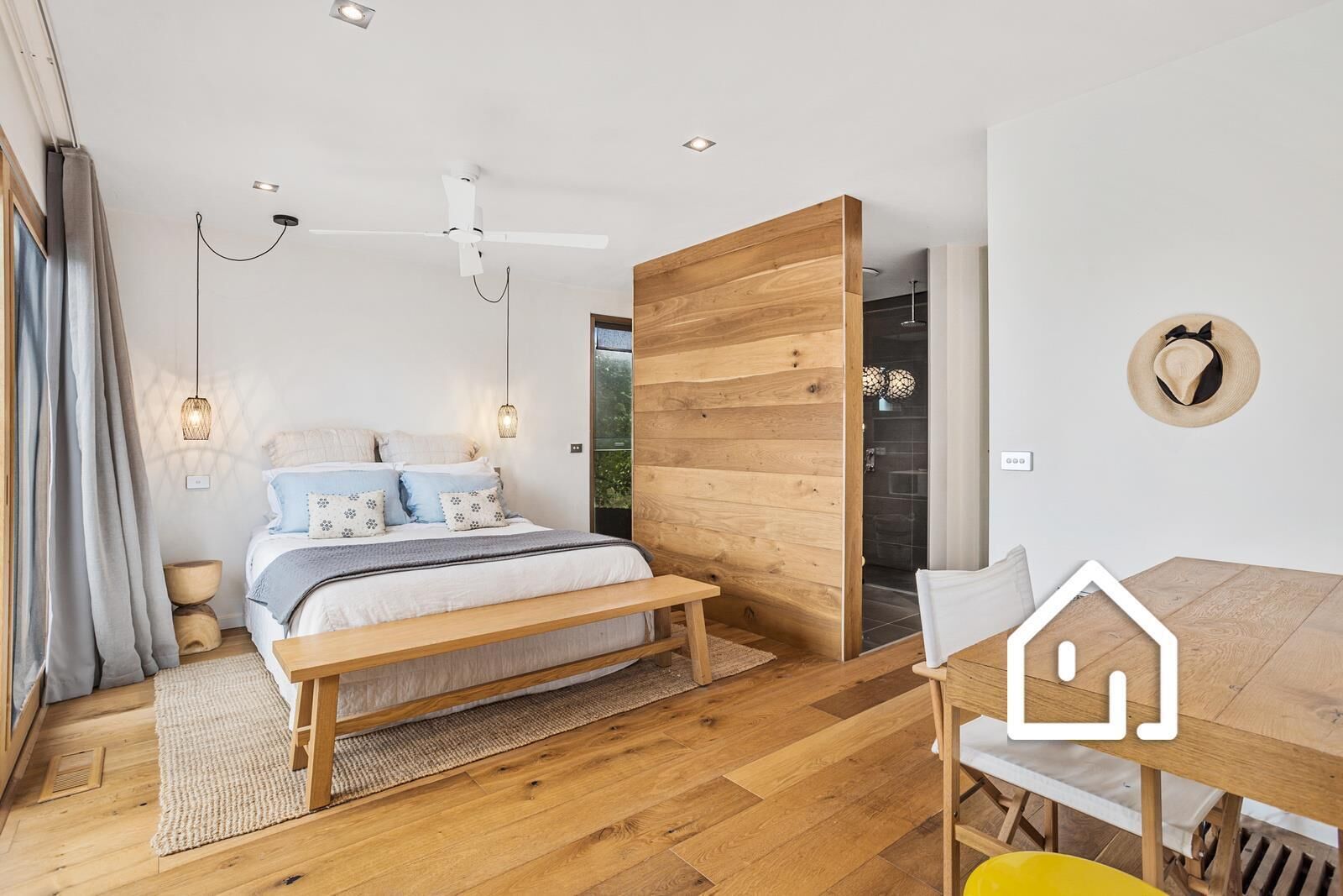 A modern bedroom with a wooden bed, a dining table, and a large window.