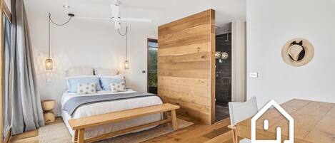 A modern bedroom with a wooden bed, a dining table, and a large window.