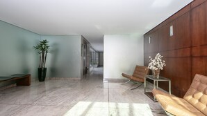 A modern lobby with a marble floor, a bench, a potted plant, a sofa, and a vase of flowers.