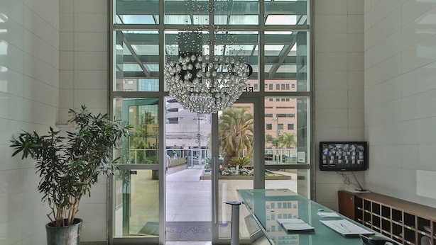A reception area with a potted plant, a glass desk, and a chandelier.