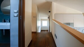 A modern hallway with a wooden floor, white walls, and a kitchen area with cabinets and a countertop. - Vista Paradiso - Appartamento "zannone" (Lazio)