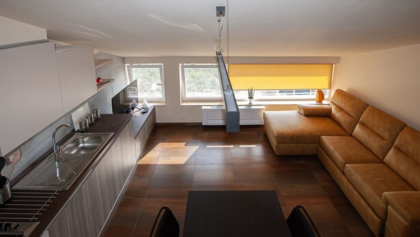 A modern kitchen with a dining area, a sofa, and a window with a view. - Vista Paradiso - Appartamento "zannone" (Lazio)