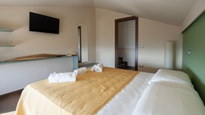 A hotel room with a bed, a desk, a flat-screen TV, and a mirror. - Vista Paradiso - Appartamento "zannone" (Lazio)