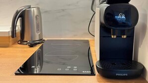 Une cuisine équipée d’une plaque de cuisson à induction noire, d’une machine à café et d’une bouilloire.