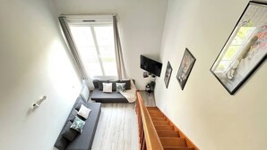Un salon moderne avec un ensemble de canapés, un téléviseur à écran plat et un escalier.