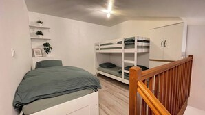 Une chambre avec un lit simple, un lit superposé et une armoire.