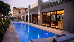 Ein moderner Poolbereich im Freien mit Liegestühlen und einem Gebäude mit großen Fenstern.
