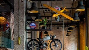 Ein Café mit rustikaler Backsteinwand, hängenden Fahrrädern und einer alten Kasse.