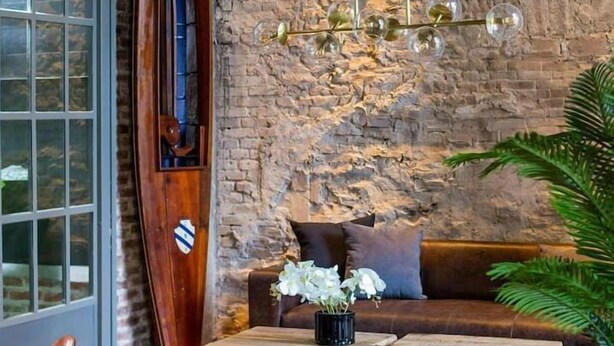 Ein gemütliches Interieur mit einem hölzernen Surfbrett, einem Ledersofa und einer Pendelleuchte.