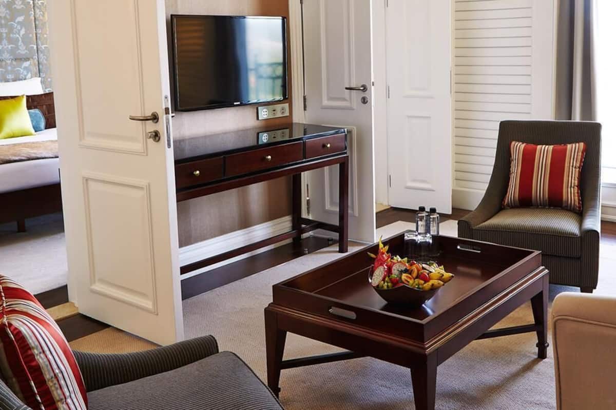 A living room with a sofa, armchair, coffee table, TV, and a desk with a computer.