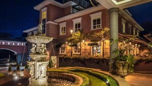 A well-lit building with a fountain, a landscaped garden, and a covered outdoor seating area. - Travelers Safari - Westlands (Nairobi)