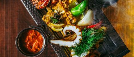 A tray of grilled seafood and vegetables on a wooden table.