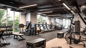A gym with various exercise equipment, large windows, and a view of palm trees. - Premier Studio with King Bed and Queen Sofa-bed (Miami)