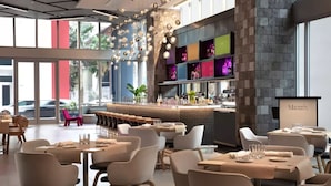 A modern restaurant with a bar area, seating for 20 guests, and large windows offering a view of the street. - Premier Studio with King Bed and Queen Sofa-bed (Miami)