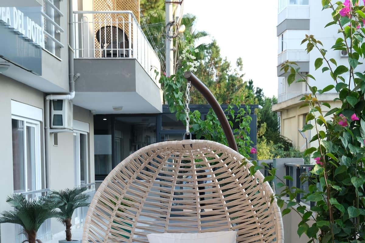 Ein Korbsessel mit Kissen auf einem Balkon.