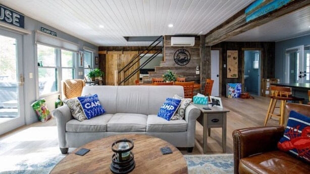 A modern living room with a grey sofa, a wooden coffee table, and a brown leather armchair. - Camp Quality Time on Wilson Lake 3-bedroom, hot tub (Wilton)