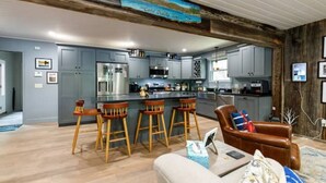 A modern kitchen with grey cabinets, a central island with stools, and a bar area. - Camp Quality Time on Wilson Lake 3-bedroom, hot tub (Wilton)